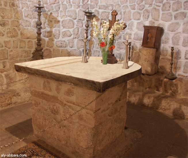la table du maître-autel -المذبح - de forme empreintée des temples païens, elle a l'aspect d'un demi-cycle à bord saillant pour retenir le sang des animaux sacrifiés et le laisser s'écouler par un orifice 